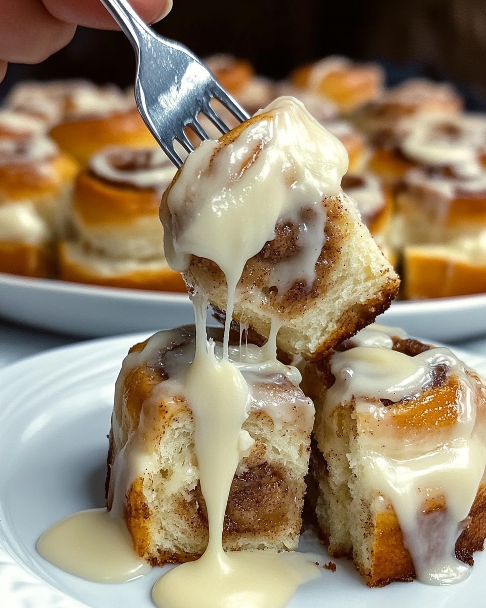 The image shows a close-up of a white plate with a single cinnamon roll piece on it, topped with a thick layer of creamy white icing. The cinnamon roll has a golden brown, slightly crispy outer layer with soft, fluffy inner layers that show some swirls of cinnamon. A woman's hand holds a fork lifting a piece of cinnamon roll generously covered in smooth, glossy icing that drips slightly. In the background, there is a white plate filled with more cinnamon rolls with similar golden brown tops and a dollop of white icing on each. The surface beneath the plates is a white marbled texture. Photo taken with an iphone --ar 4:5 --v 6.1