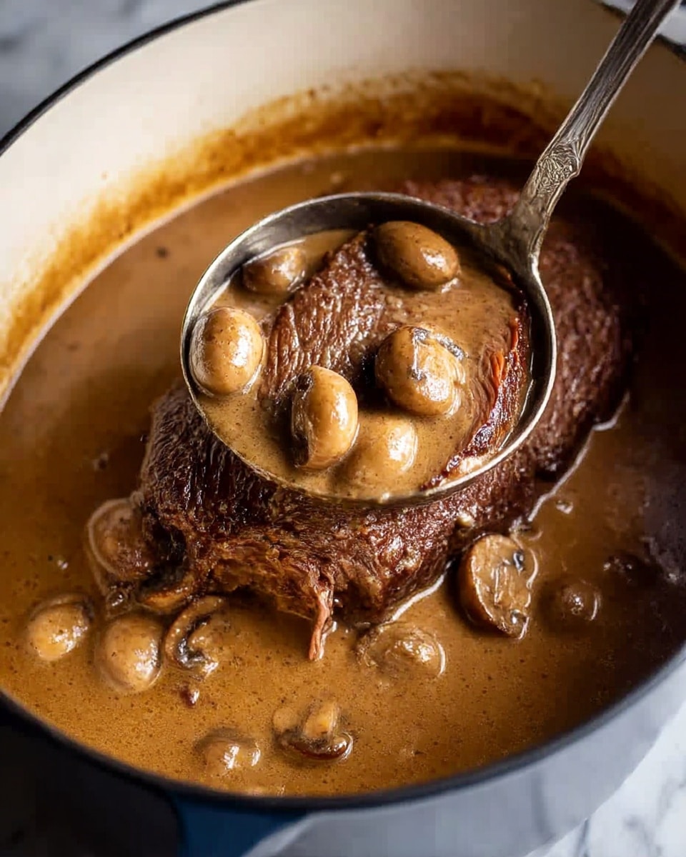 A dark brown cooked beef roast sits in a large white pot filled with a thick, creamy brown gravy. The gravy contains whole small mushrooms, visible both in the pot and in a silver ladle held above the roast. The roast looks tender with a slightly textured surface and a rich brown color. The white marbled background underneath the pot contrasts with the dark tones of the beef and sauce, highlighting the dish's hearty and rustic feel. Photo taken with an iphone --ar 4:5 --v 6.1