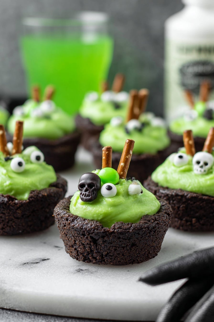 Cauldron Cookie Cups, Halloween Cookie Cups, Festive Cookie Dessert, Easy Halloween Treats, Fun Halloween Baking - The image shows small dark brown cookie cups filled with bright green creamy frosting. Each frosting has small white and green candy decorations shaped like skulls and eyeballs, giving a spooky look. A small pretzel stick is inserted into the frosting on each cup, standing upright. The cookie cups are placed on a white marbled surface, and in the background is a blurry green drink and a white bottle with black text. A woman's hand in a black glove is reaching towards the cookie cups from the right side. photo taken with an iphone --ar 2:3 --v 7