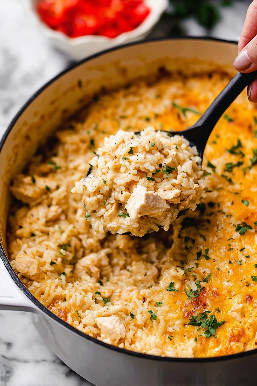 One Pot Queso Chicken and Rice, cheesy chicken and rice skillet, creamy queso chicken recipe, easy one pot dinner, quick weeknight chicken recipes - This image shows a close-up of a white pot filled with a creamy, cheesy rice dish. The dish has one main layer of cooked rice mixed with small pieces of chicken and sprinkled with chopped green herbs. The rice looks soft and slightly orange-yellow from the cheese sauce that covers it evenly, with some melted cheese visible on top near the edges. A black spoon lifted by a woman's hand holds a scoop of the rice mixture in the center of the pot. The background shows a blurred white bowl with chopped red tomatoes. The whole scene is set on a white marbled surface. photo taken with an iphone --ar 2:3 --v 7