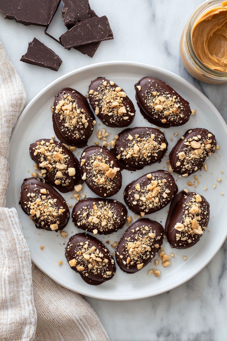 Date Snickers, healthy date snickers, homemade candy bars, no-bake snack, best date snickers recipe - A white plate holds a dozen small oval treats, each fully covered in smooth dark chocolate with a shiny finish. On top of every treat, there is a sprinkling of light brown crushed nuts, adding a rough texture. The plate rests on a white marbled surface, with pieces of dark chocolate on the left and a jar filled with creamy light brown peanut butter on the right side. A beige and white striped cloth is placed next to the plate on the left. photo taken with an iphone --ar 2:3 --v 7