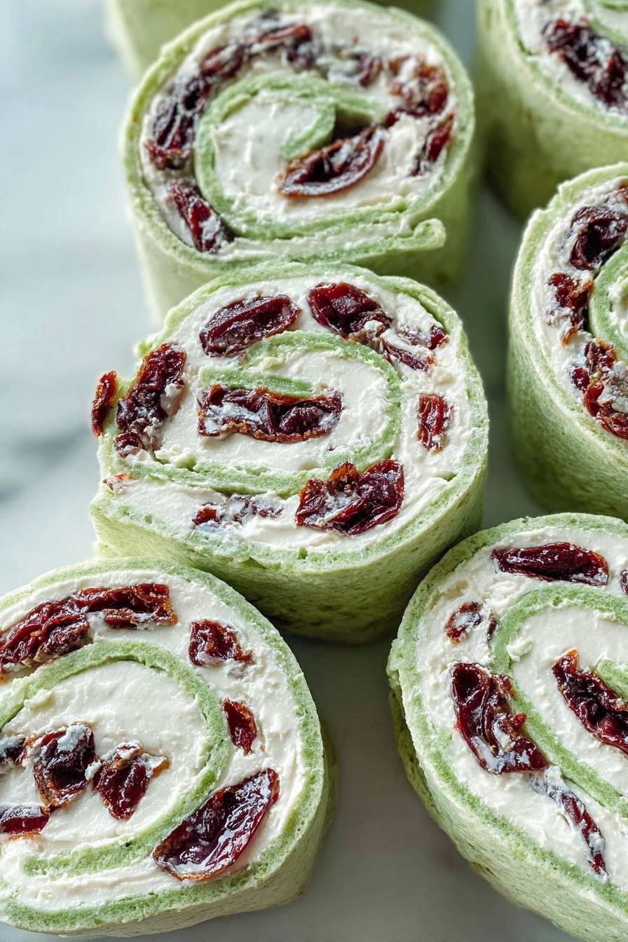 Cranberry Feta Pinwheels, Cranberry Feta Wraps, Easy Cranberry Appetizer, Holiday Cranberry Snacks, Cream Cheese Pinwheels - The image shows several spiral pinwheel wraps arranged closely on a white marbled surface. Each wrap has three visible layers: the outer layer is a light green soft flatbread, the middle layer is a thick white creamy filling, and the innermost layer consists of dark red dried fruit pieces evenly spread throughout. The wraps are sliced to show the spiral pattern clearly, with the green flatbread curling around the white filling and red fruit in a tight spiral. The texture of the flatbread looks soft and slightly porous, while the filling is smooth and creamy. Photo taken with an iphone --ar 2:3 --v 7