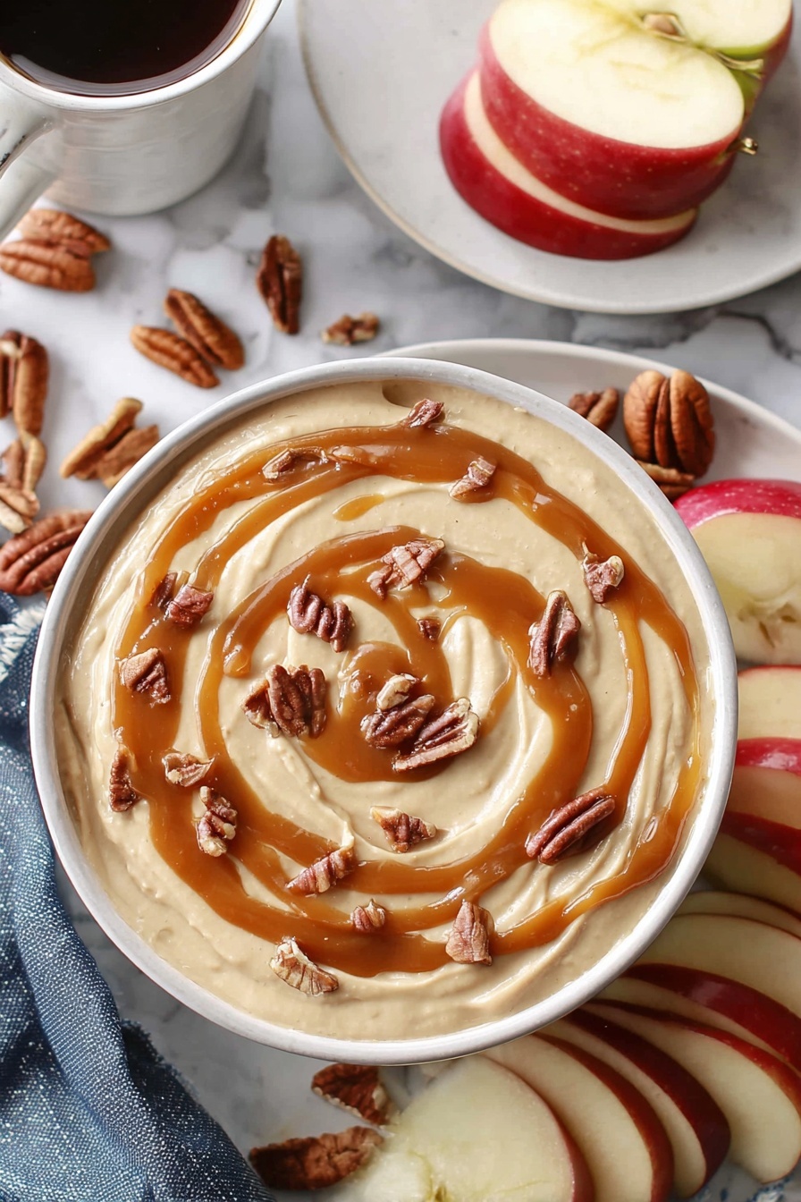 Caramel Cheesecake Dip, easy caramel cheesecake dip, quick dessert dip, creamy caramel cheesecake, luscious caramel dip - A white bowl holds a creamy beige dip that fills it nearly to the top, with smooth swirls of caramel sauce drizzled in a loose spiral on the surface. Small pieces of brown pecans are scattered evenly over the caramel, adding texture and contrast. Around the bowl, slices of red apple with white insides sit beside whole pecans. In the background, a white plate holds more apple slices, and a white marbled surface surrounds everything. A woman's hand holds a white cup filled with a dark drink near the top left corner. photo taken with an iphone --ar 2:3 --v 7