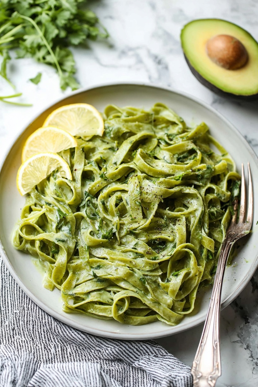 Avocado Lemon Pesto, quick healthy pesto, nut-free pesto, creamy avocado sauce, citrusy pesto - A clear blender jar with four sharp blades at the bottom contains a thick, smooth mixture of bright green color with a slight creamy texture. The blender base beneath is black with a large round silver knob in the center. The jar handle is transparent with a blue tint, positioned to the right, and the whole scene is set on a white marbled surface. photo taken with an iphone --ar 2:3 --v 7