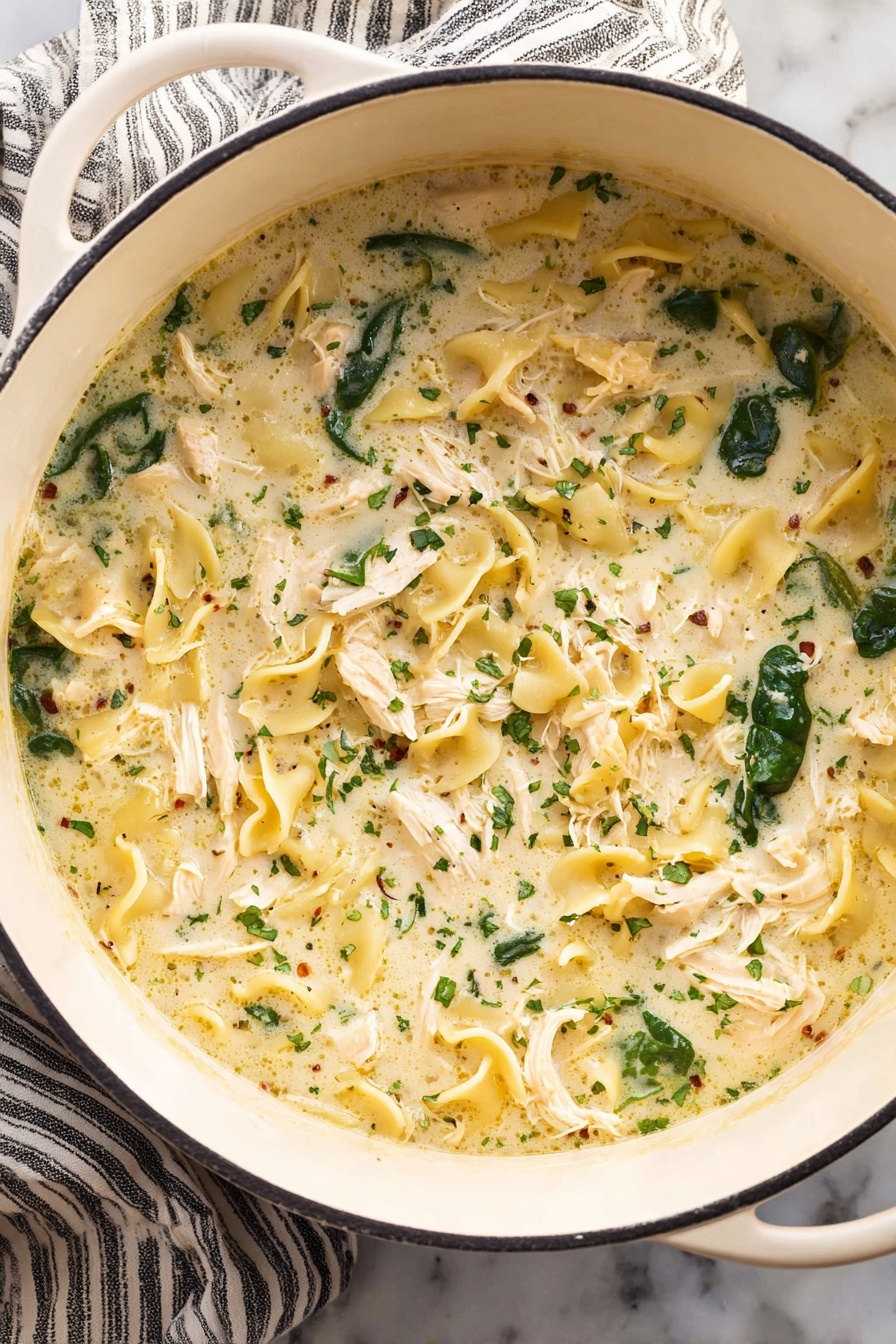 White Lasagna Soup, White Lasagna Soup Recipe, Italian creamy soup, easy weeknight dinner, cheesy chicken soup - A white pot filled with creamy soup that has three main layers: shredded white chicken pieces spread evenly, dark green spinach leaves scattered throughout, and curly, pale yellow pasta floating in a thick, light cream broth with small herbs sprinkled all over. The pot is placed on a white marbled surface with a striped cloth under one side. Photo taken with an iphone --ar 2:3 --v 7