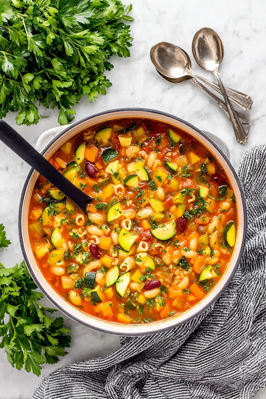 Easy Minestrone Soup, hearty vegetable soup, healthy minestrone recipe, quick vegetarian soup, comforting Italian soup - A close-up of a white pot filled with colorful minestrone soup, showing about five layers of ingredients in a light red broth. The soup contains small pasta shells, dark red kidney beans, orange carrot cubes, yellow and green zucchini slices, green celery pieces, and diced tomatoes. A ladle is lifting a scoop of soup with a mix of these ingredients, showcasing their textures and colors. The background has a white marbled texture with some green herb leaves visible around the pot. Photo taken with an iphone --ar 2:3 --v 7