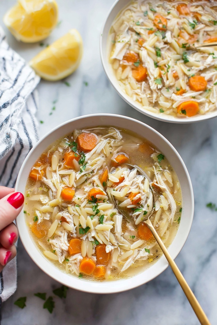 Lemon Chicken Soup with Orzo, lemon chicken soup, comforting chicken soup, easy lemon soup, healthy chicken and orzo soup - Two white bowls filled with soup sit on a white marbled surface, each bowl holding a mix of shredded light brown chicken, small round orange carrot slices, and pale yellow orzo pasta floating in a light broth. Bright green herbs are sprinkled throughout the soup, adding fresh color. A gold spoon is held by a woman's hand with red painted nails, lifting a spoonful of soup from the bowl in the front, showing a clear view of the ingredients. In the background, a lemon half and a white-and-blue striped cloth are softly out of focus. photo taken with an iphone --ar 2:3 --v 7