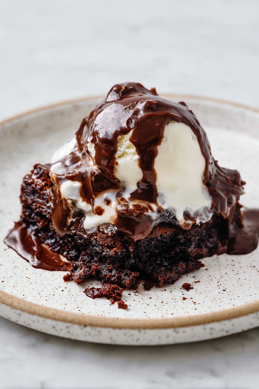 Easy Hot Fudge Cake, hot fudge cake, chocolate self-saucing cake, quick chocolate dessert, cozy chocolate cake - A white speckled plate holds a dessert with three main layers. The bottom layer is a dark brown, moist chocolate cake with a rough, crumbly texture. On top of this is a soft, white scoop of melting ice cream that is smooth and creamy. The top layer is thick, glossy dark chocolate sauce, generously poured over the ice cream and cake, flowing and blending into the layers below. The plate sits on a white marbled surface. photo taken with an iphone --ar 2:3 --v 7