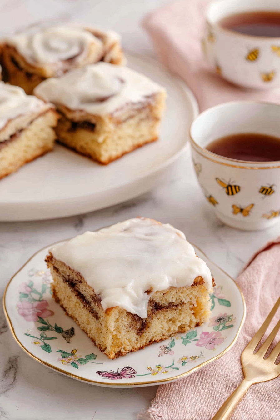 Cinnamon Roll Cake, cinnamon roll cake recipe, easy cinnamon cake, sheet cake cinnamon roll, cinnamon dessert recipe - The image shows three square pieces of cinnamon roll cake with a light brown base and a visible swirl of darker cinnamon filling inside. Each piece is topped with a thick, creamy white icing that spreads unevenly on top. The pieces sit on white plates with delicate gold edges and small floral designs. A white teacup with a gold line on the rim and small floral pattern holds dark brown tea, positioned beside one of the plates. A gold fork rests on a soft pink napkin near the front plate. The background is a white marbled surface, and a tray with more pieces is visible in the back. Photo taken with an iphone --ar 2:3 --v 7