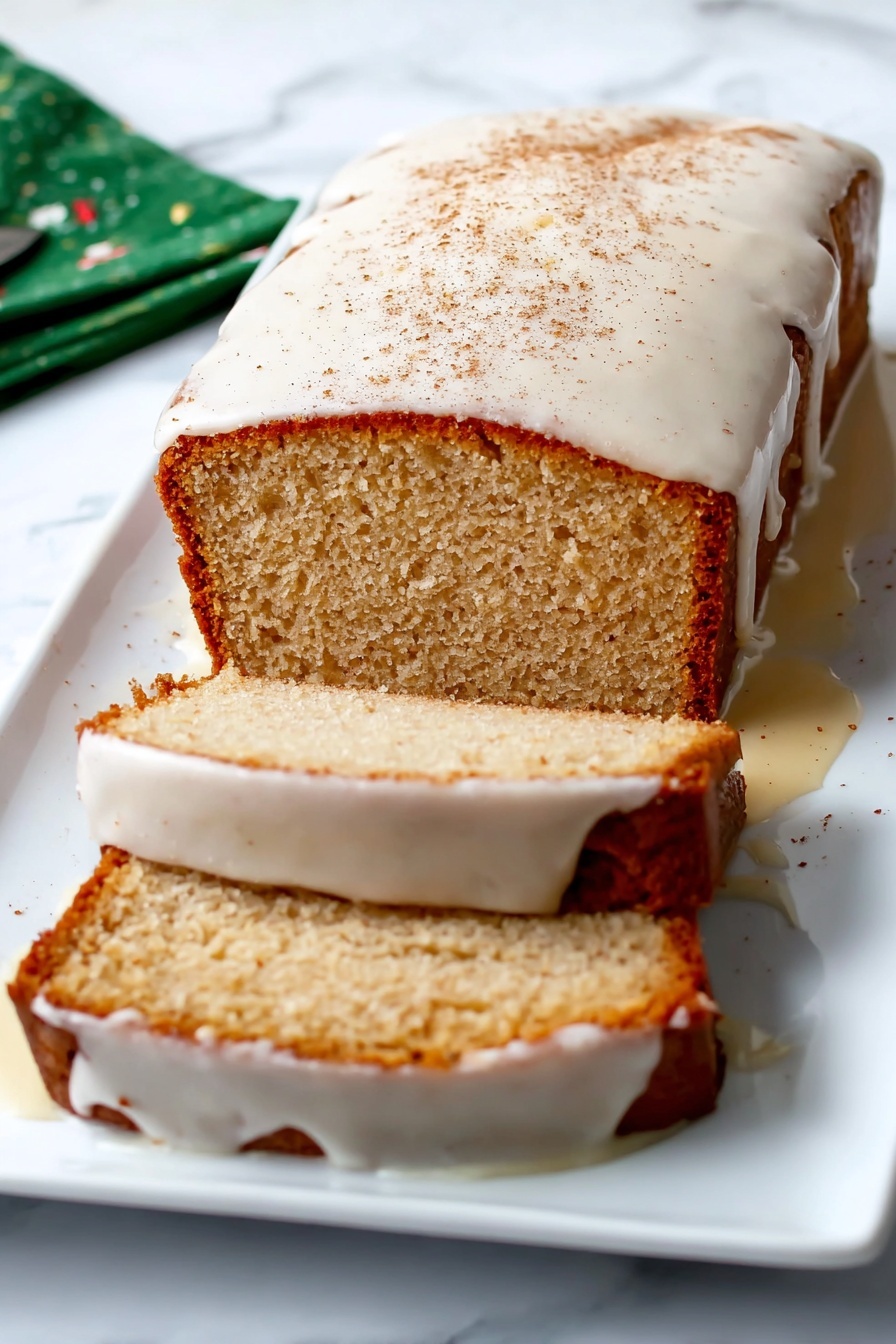 Eggnog Bread Christmas Bread Holiday Sweet Bread Festive Baking - A loaf cake with a light brown crust sits on a white rectangular plate against a white marbled surface. The cake is sliced twice, with two visible slices lying flat next to the main loaf. A thick white glaze covers the top of the cake, dripping over the sides and partly onto the plate, with a light dusting of cinnamon on top. The inside of the cake is a soft beige color with a slightly crumbly texture. Photo taken with an iphone --ar 2:3 --v 7
