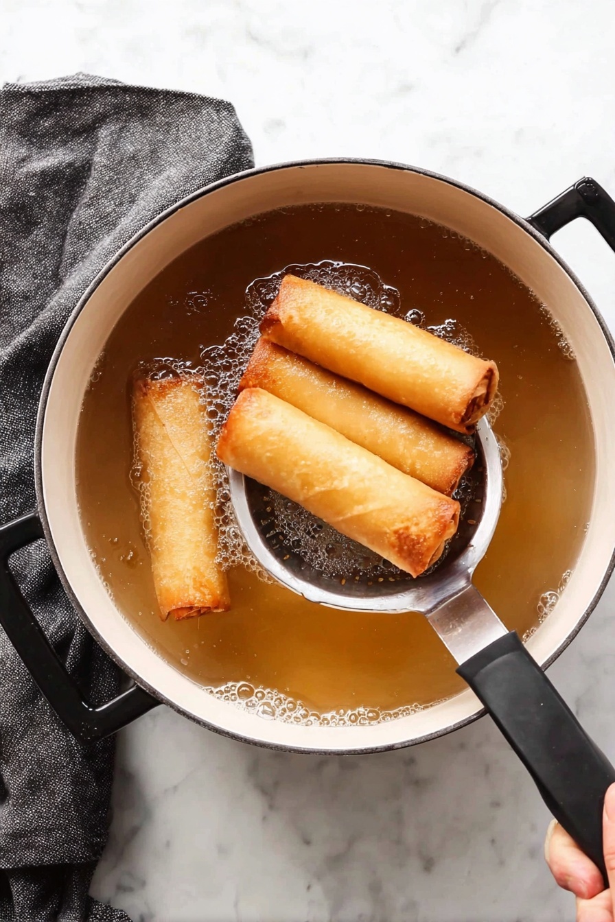 Vegetable Spring Rolls with Crispy Wrapper, vegetarian spring rolls, healthy spring roll recipe, crispy veggie spring rolls, easy spring roll ideas - A white pot with black handles is filled with light brown hot oil, frying four golden spring rolls that are crispy and smooth on the outside. A stainless steel slotted spoon holds three spring rolls gently above the oil while a woman's hand holds the pot’s black handle. The white marbled surface beneath has a folded dark gray towel on the left side. The scene shows the texture of the cooked spring rolls with a small amount of bubbles around them in the oil photo taken with an iphone --ar 2:3 --v 7